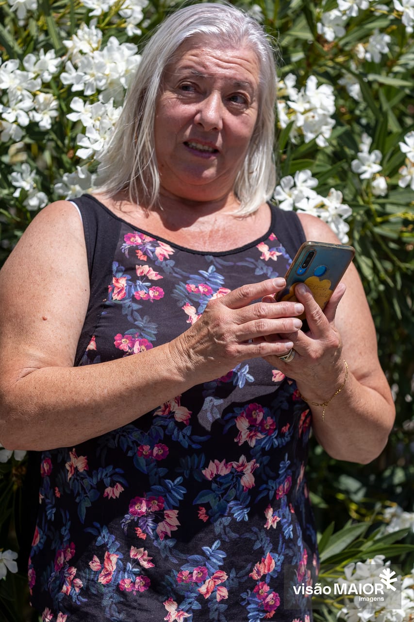Mulher de cabelos brancos com telemóvel nas mãos