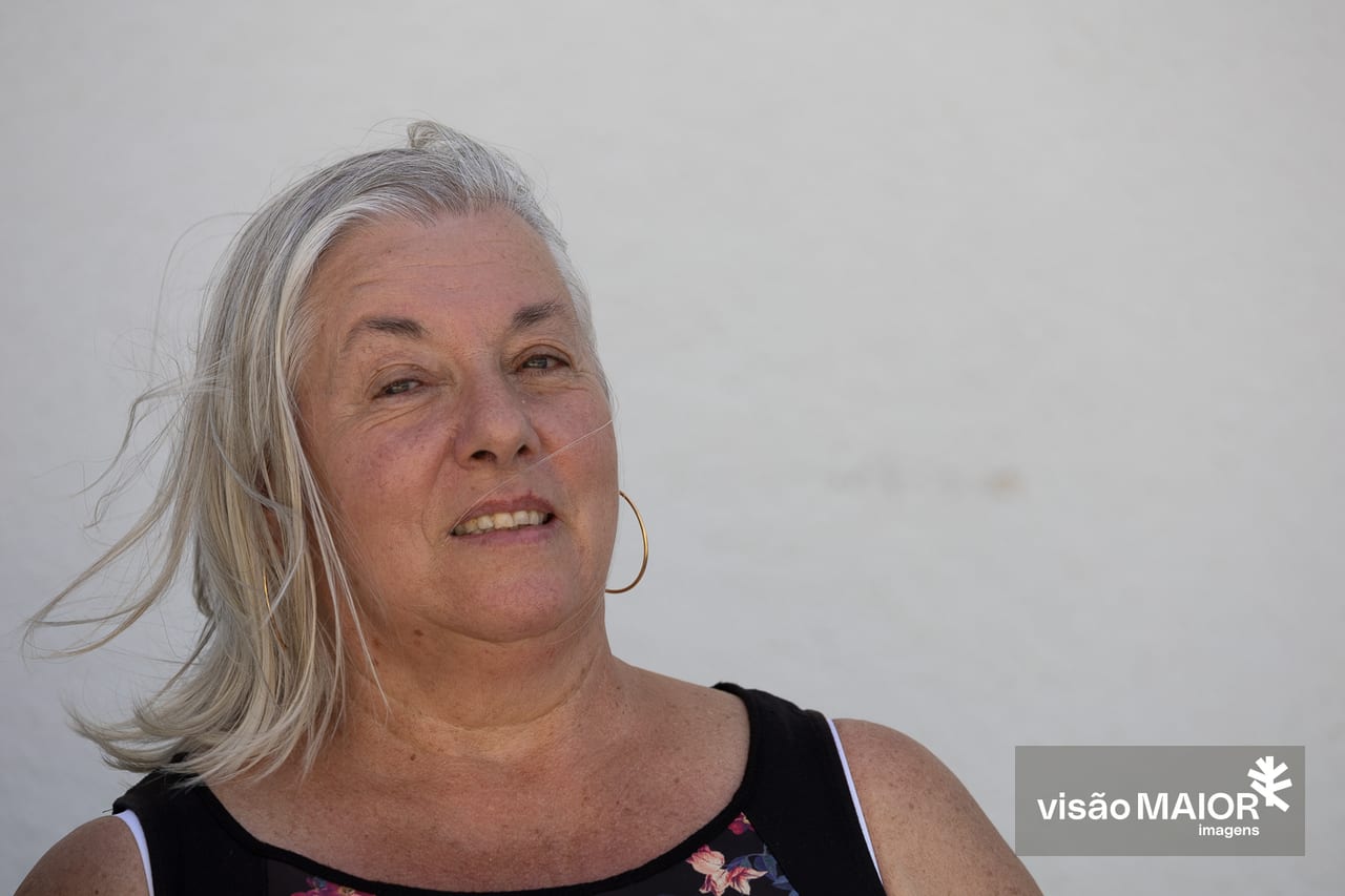 Mulher de cabelos brancos e brincos com cabelo ao vento