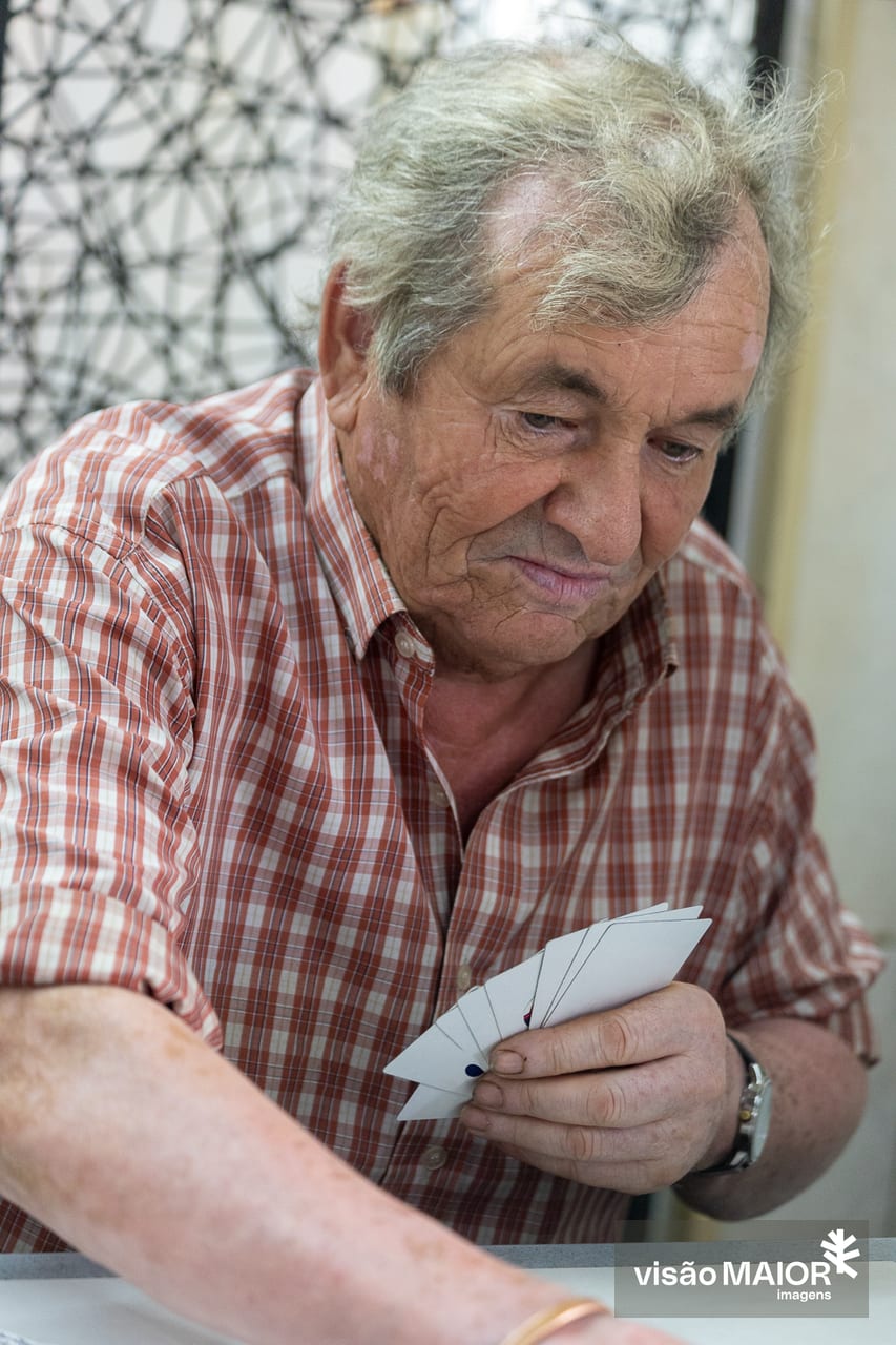 Homem de cabelo grisalho e camisa aos quadrados a jogar cartas